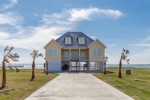 A two-story house with a balcony, a garage, and a view of the water.