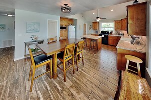 A spacious kitchen with wooden cabinets, a dining area with a table and chairs, and a bar area with stools.