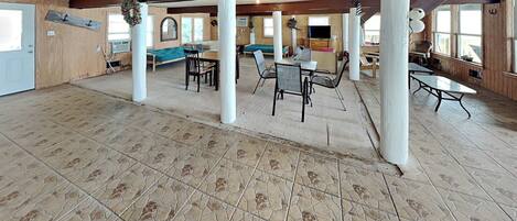 A spacious room with a high ceiling, wooden beams, and a tiled floor.