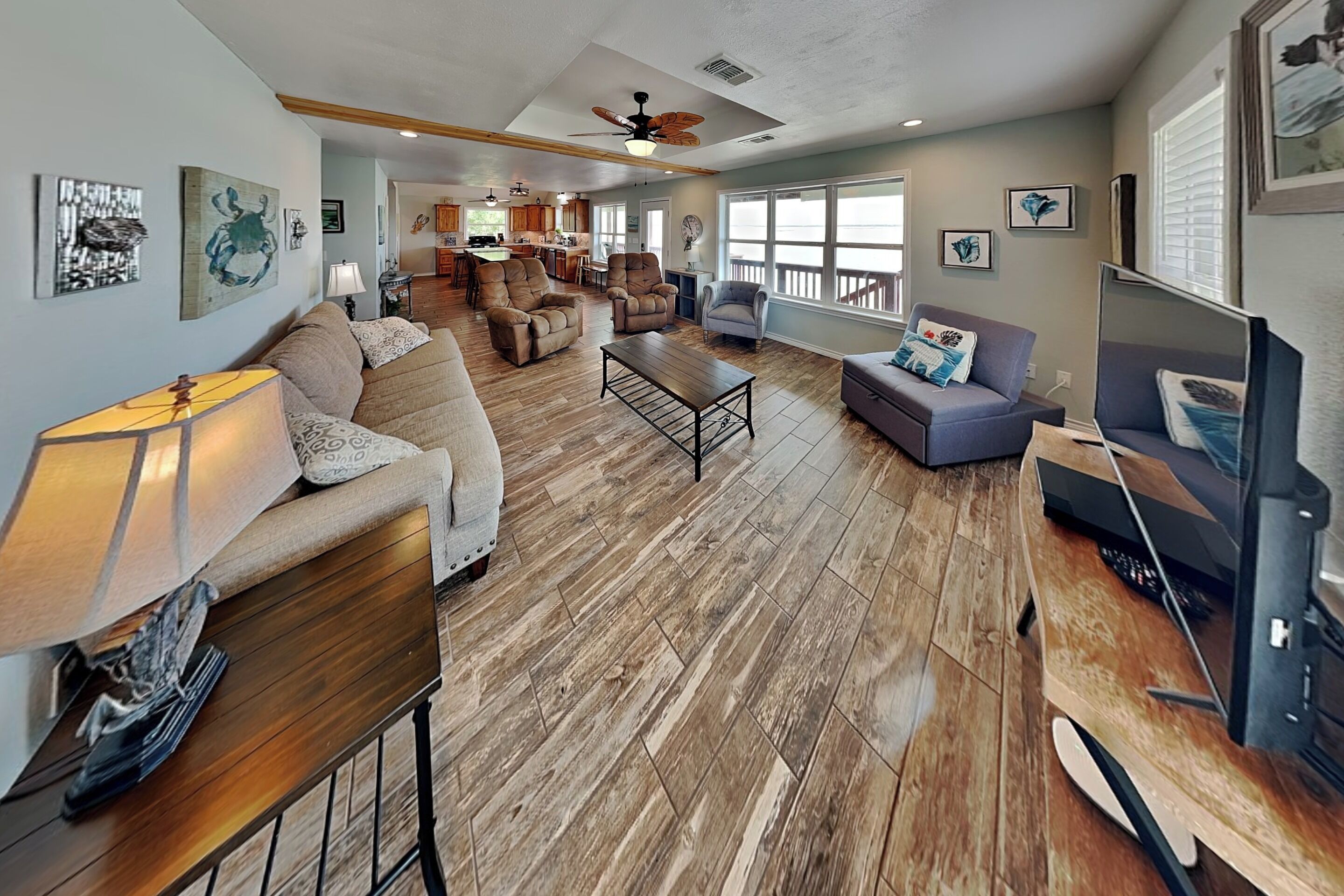 A spacious living area with a wooden floor, a sofa, a coffee table, and a television.