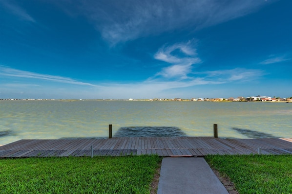 A wooden dock extending into a calm body of water with a clear sky above. - Waterfront Escape by Miss Kitty’s (Rockport)