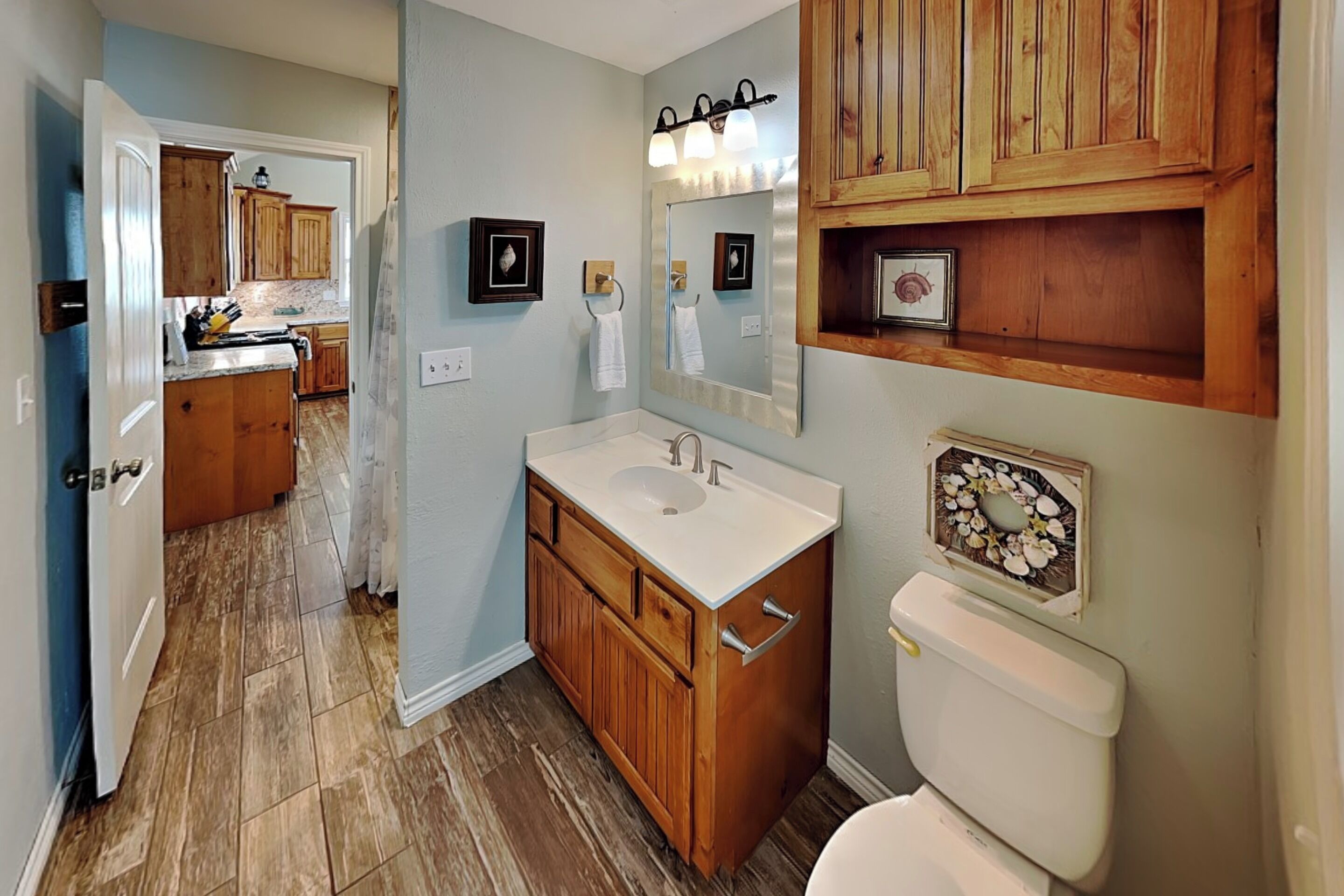 A bathroom with wooden cabinets, a sink, and a toilet.