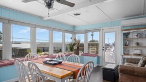 A dining area with a table and chairs, a ceiling fan, and a view of the outside. - Texas Tiki by Miss Kitty’s (Rockport)
