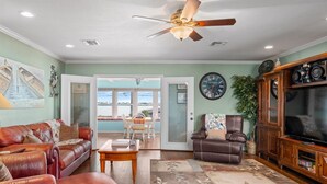 A spacious living room with a leather sofa, a brown leather chair, a wooden coffee table, and a television on a wooden cabinet. - Texas Tiki by Miss Kitty’s (Rockport)
