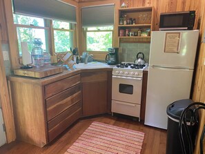 A compact kitchen with wooden cabinets, a stove, a microwave, and a refrigerator.