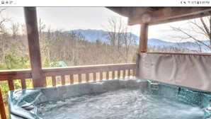 Un jacuzzi con cubierta de madera y vista a las montañas.