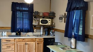 Una cocina compacta con armarios de madera, microondas, cafetera y comedor con mesa y sillas.