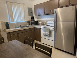 A modern kitchen with stainless steel appliances, wooden cabinets, and a dining area with a table and chairs.