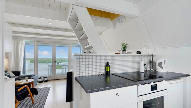 A modern kitchen with a black countertop, white cabinets, and a view to the outside. - Beautiful home in Gedser with kitchen (Gedser)