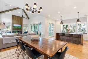Une cuisine moderne avec un îlot central en bois, des tabourets de bar et une grande table à manger.