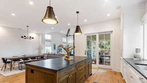 A modern kitchen with a central island, wooden cabinets, and pendant lighting.