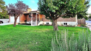 Ein zweistöckiges Haus mit Veranda, Garage und gepflegtem Rasen.