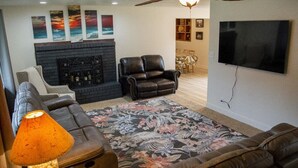 Ein Wohnzimmer mit Kamin, Ledersofas, Fernseher und Deckenventilator.