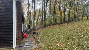 A rustic cabin with a stone pathway leading to a red chair outside.