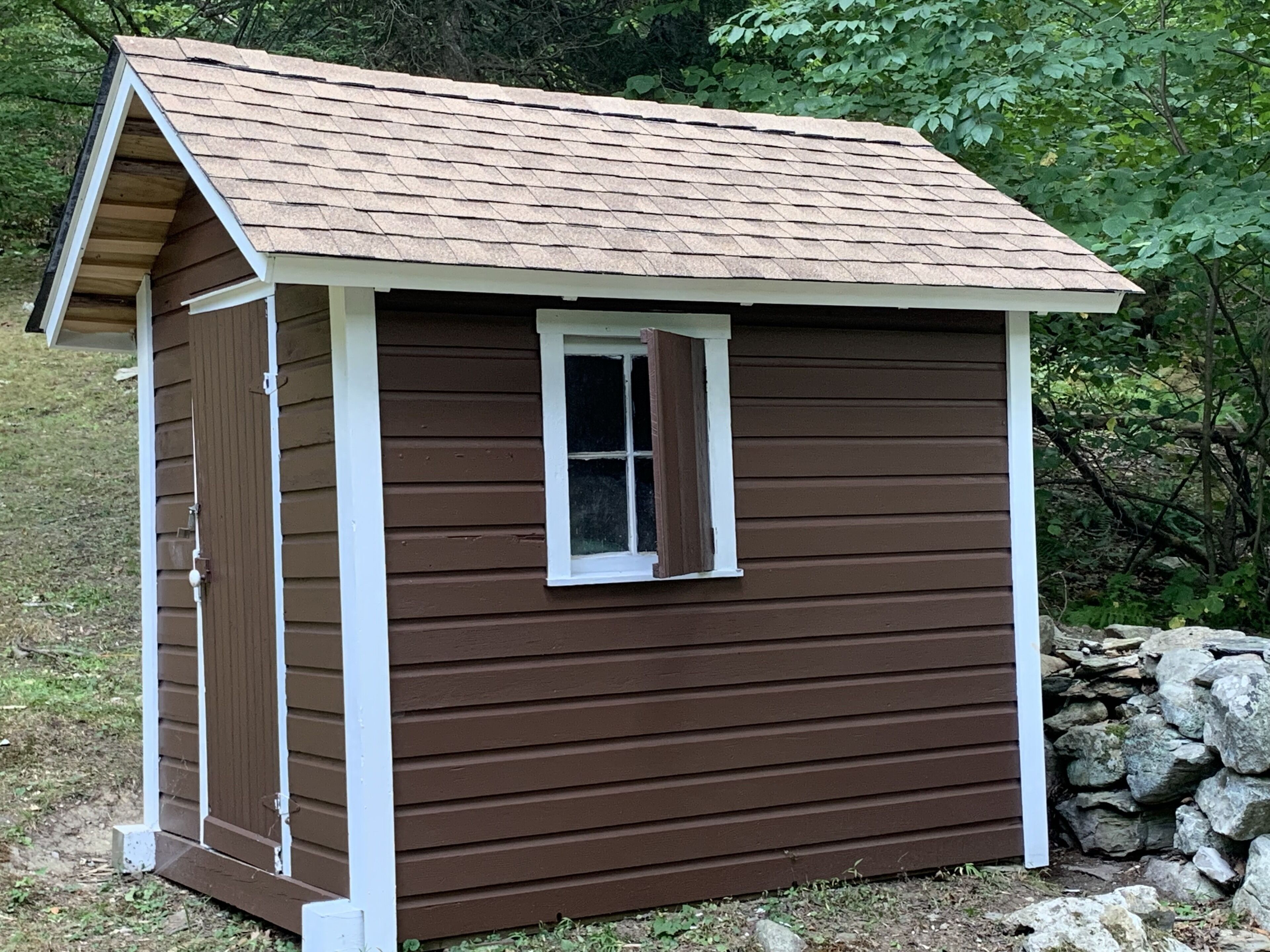 A small wooden shed with a pitched roof and a single window.