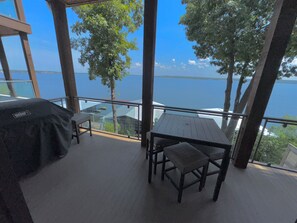 Een balkon met een tafel en stoelen, met uitzicht op een waterpartij.