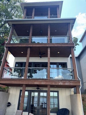 Een meerhoog gebouw met een balkon op de tweede verdieping, grote ramen en uitzicht op het water.