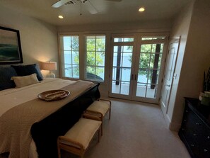 Een slaapkamer met een bed, een bankje en uitzicht op een balkon met glazen deuren.