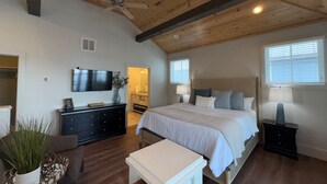 A bedroom with a bed, bedside tables, a TV, and a ceiling fan.
