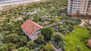 A coastal hotel with a red-roofed building, a beach view, and a well-maintained garden. - Luxury Minorca ~ Corner Unit ~ Ocean & River Views! 2 Balconies! Paros 606 (New Smyrna Beach)