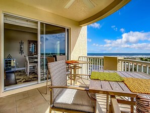 A balcony with a table and chairs, a sliding glass door, and a view of the ocean. - Luxury Minorca ~ Corner Unit ~ Ocean & River Views! 2 Balconies! Paros 606 (New Smyrna Beach)