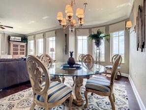 A dining area with a glass table, striped chairs, and a chandelier.