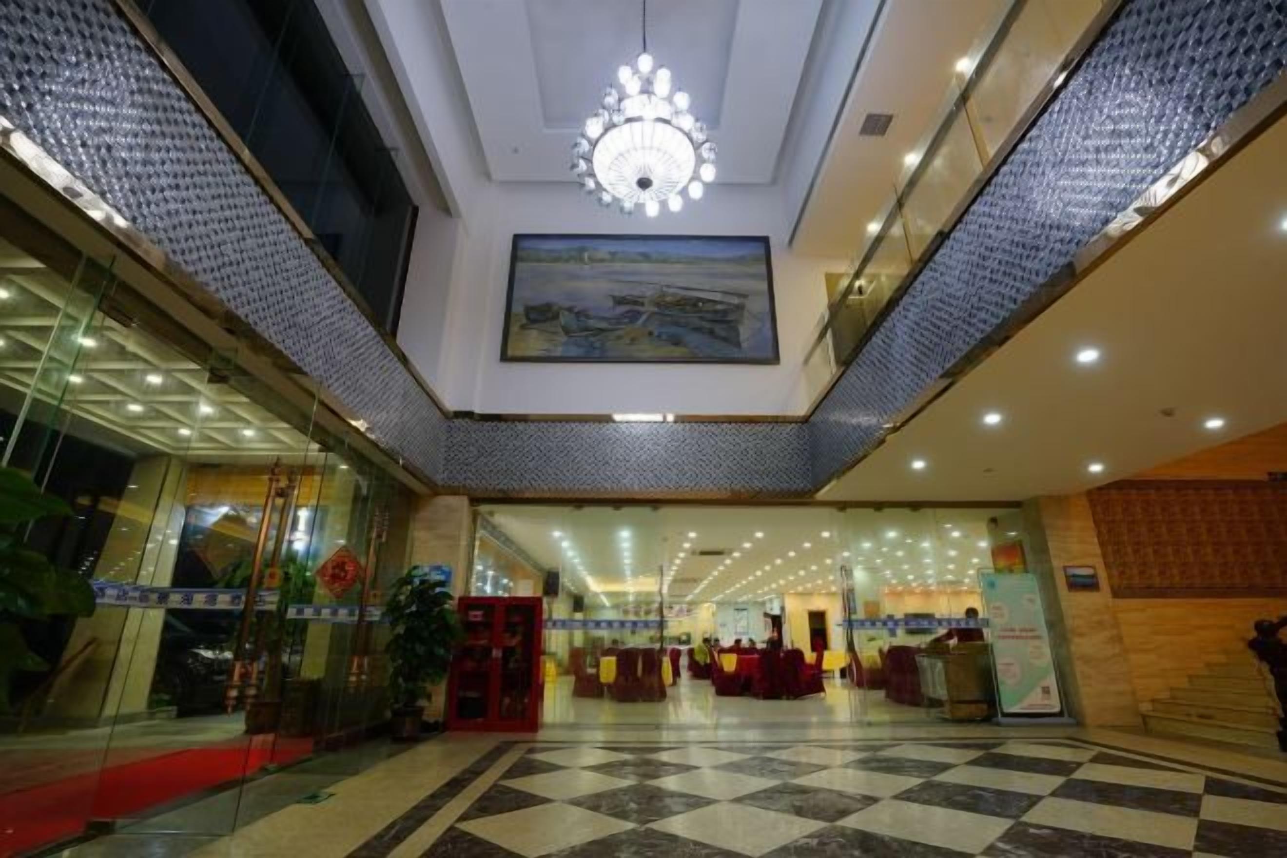 A hotel lobby with a checkered floor, a chandelier, and a painting on the wall.