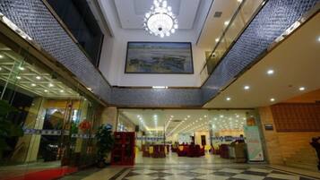 A hotel lobby with a checkered floor, a chandelier, and a painting on the wall.