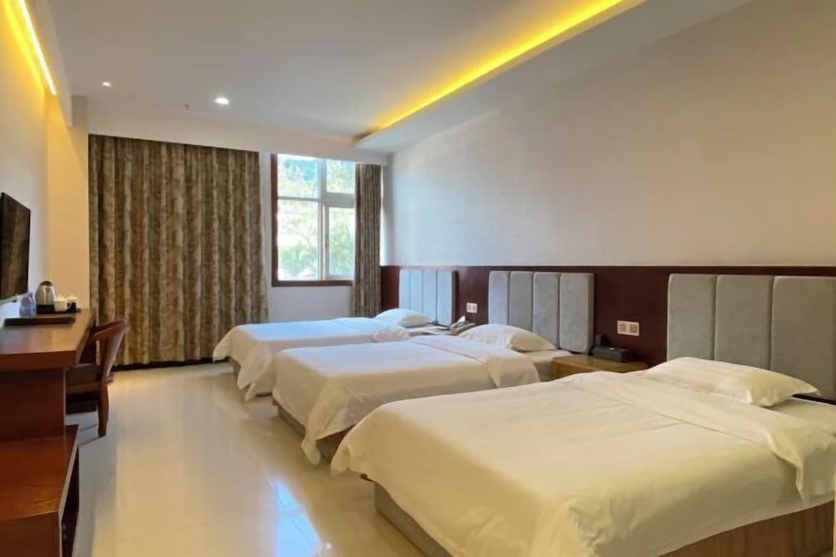 A hotel room with two beds, a desk, and a TV.