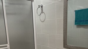 Une salle de bain équipée de toilettes, d’un lavabo et d’un miroir sur lequel est accrochée une serviette.