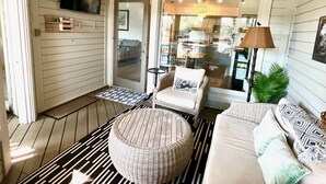A spacious living area with a ceiling fan, a sofa set, a round wicker ottoman, and a dining table with chairs. - Courtside Paradise by Sandpiper | Near Beach (Seabrook Island)