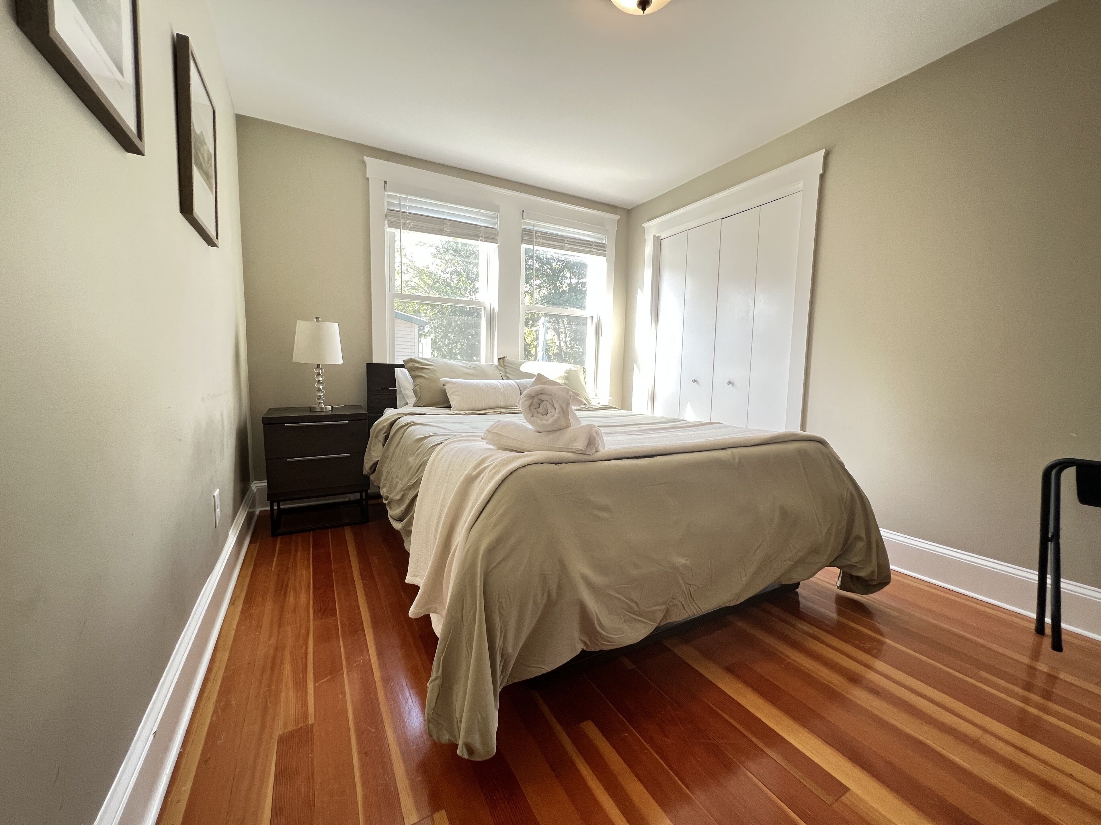 A bedroom with a bed, nightstand, lamp, and a window with blinds.