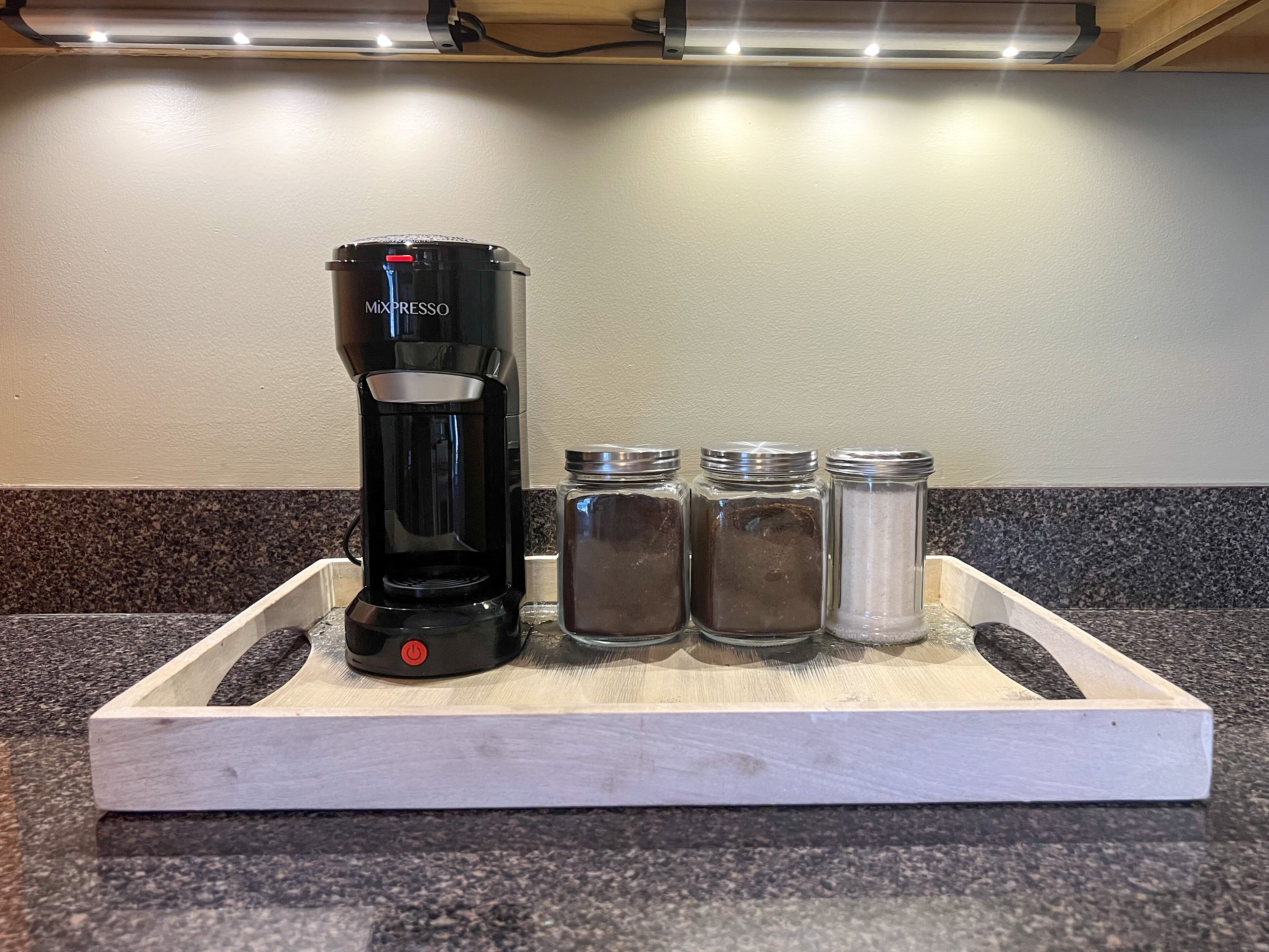 Une machine à café portant la marque « Mixpresso » est posée sur un plateau, à côté de trois salières.
