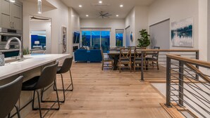 Une cuisine moderne avec un coin bar, un plancher en bois et une vue sur le salon.