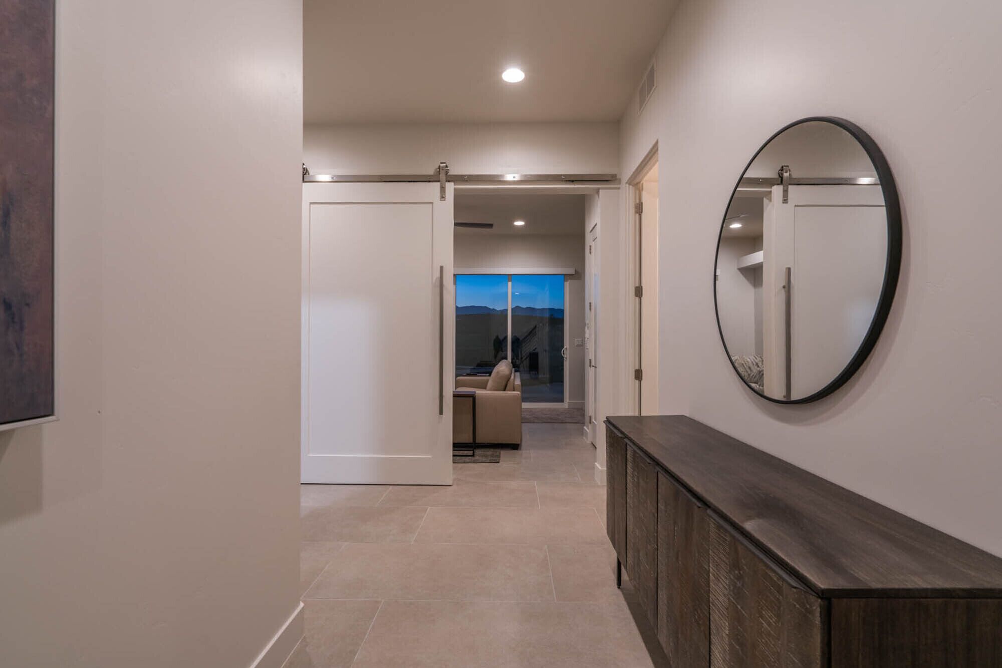 A hallway with a sliding door leading to a balcony with a view of the mountains.