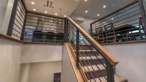 Un escalier moderne avec des rampes en bois et des garde-corps en métal, menant à un niveau inférieur.