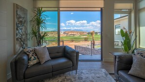 Un vaste salon doté d’une grande porte-fenêtre coulissante donnant sur un balcon avec vue sur un terrain de golf.