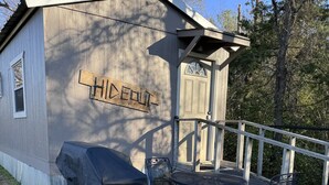 Un cobertizo de madera con la etiqueta "THIDENUT", una parrilla cubierta y asientos al aire libre.