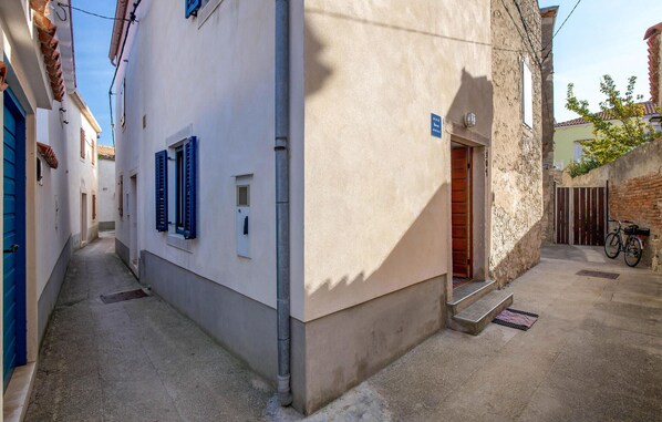 Une rue étroite avec un bâtiment qui présente une porte et une fenêtre avec des volets.
