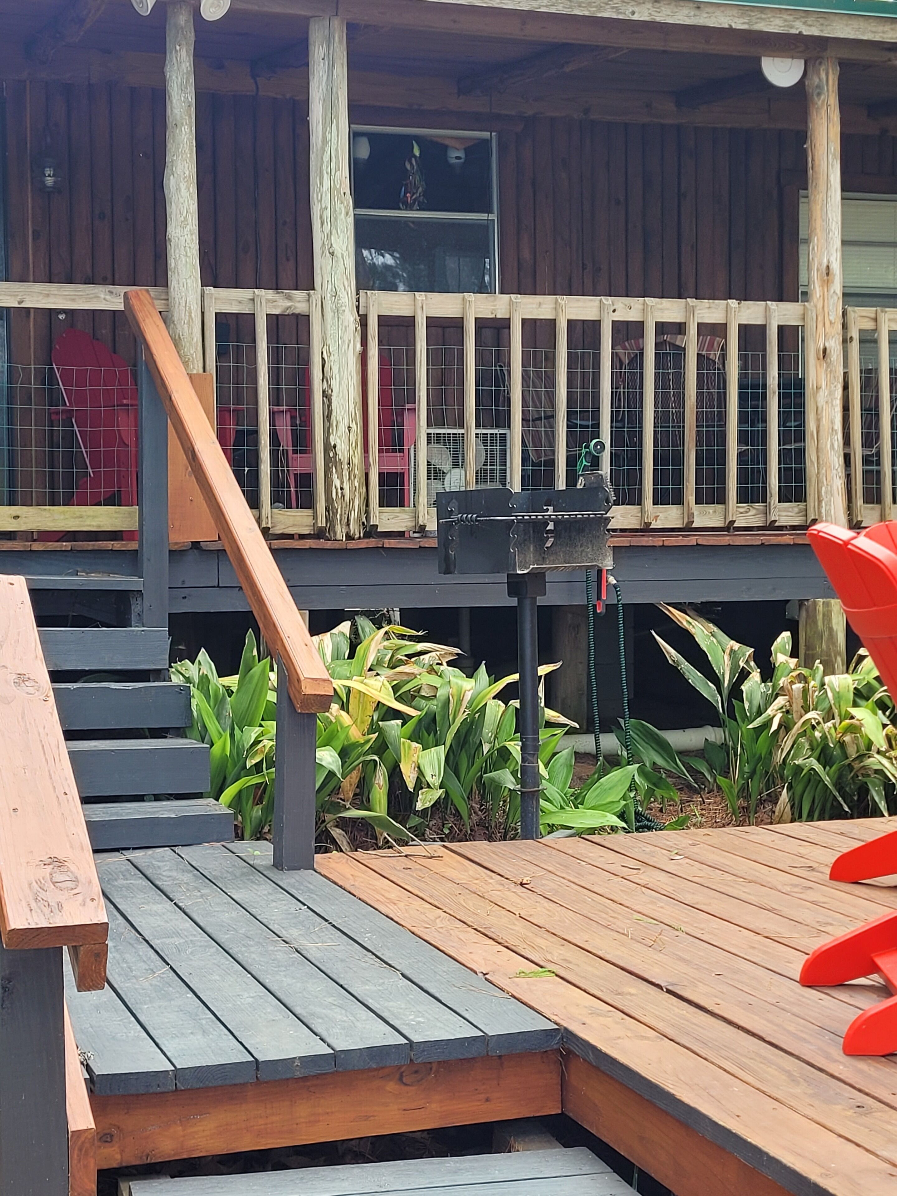 A wooden deck with a ramp leading to a covered area with a window.
