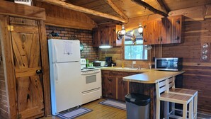 Una cocina rústica con armarios de madera, un refrigerador blanco, una estufa, un microondas y un lavamanos.