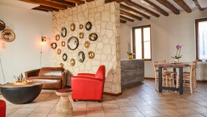 Ein Wohnzimmer mit Steinwand, Ledersofa, rotem Sessel und rundem Couchtisch.