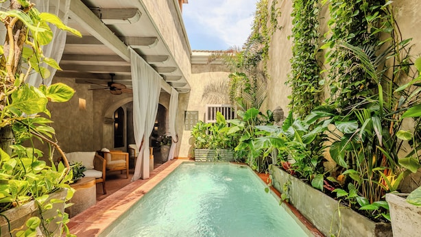 A pool area with a ceiling fan, wicker furniture, and lush greenery. - Moet Cartagena Hotel Boutique  - Adults Only (Cartagena)