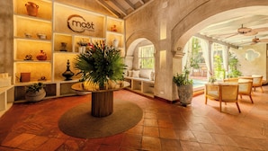 A cozy interior with a central round table, shelves with decorative items, and seating areas with wicker chairs. - Moet Cartagena Hotel Boutique  - Adults Only (Cartagena)