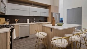 A modern kitchen with white cabinets, a central island, and gold chairs. - Historic Charm + Modern Comfort for Tourists (Chicago)