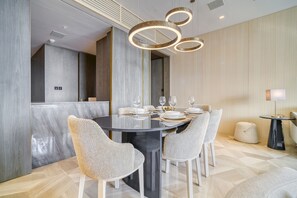 A modern dining area with a round table, four chairs, and a contemporary light fixture.