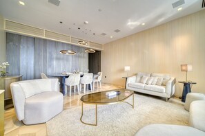 A modern living room with a sofa, armchairs, a glass coffee table, and a dining area with a table and chairs. - Modern Sea View Apt. at the FIVE Palm Jumeirah (Dubai)