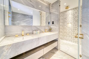 Une salle de bain moderne avec un grand miroir, deux lavabos et un espace douche.