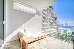 A modern apartment with a white sofa, a wooden bench, and a city view.