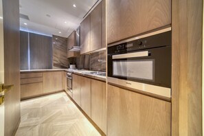 A modern kitchen with wooden cabinetry, stainless steel appliances, and a herringbone-patterned floor.